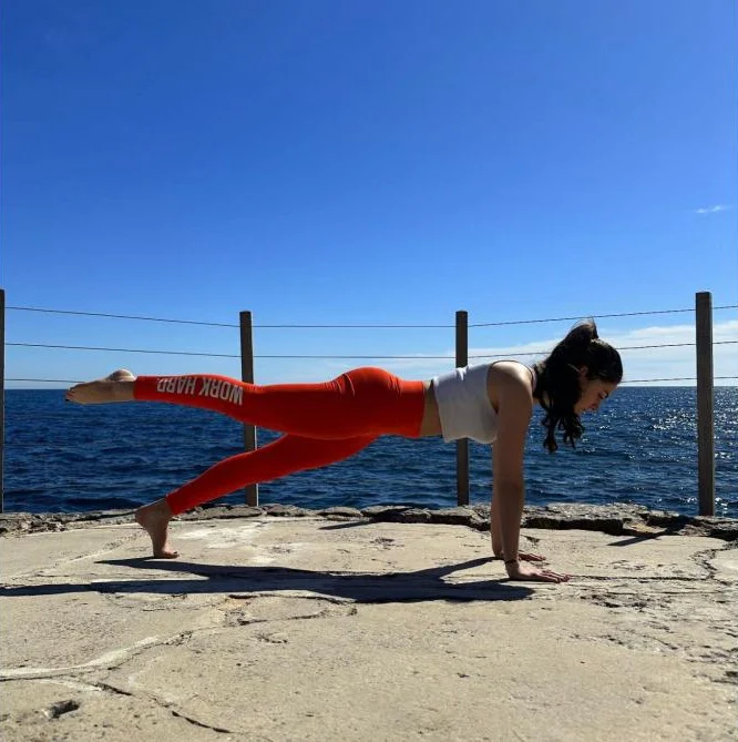 Marina, instructrice Pilates, en planche face à la mer